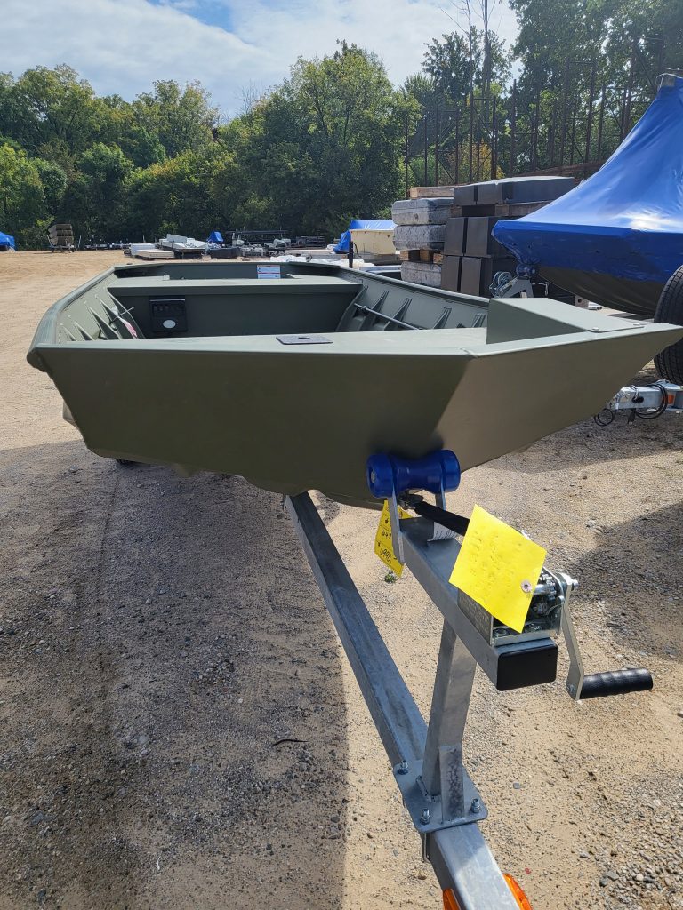 A small fishing or utility boat displayed outdoors at Camp & Cruise, ready for sale.