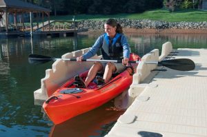 Bright red kayak on the water at Camp & Cruise, with a woman enjoying kayaking activity.
