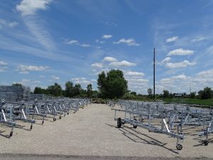 Boat trailer storage at Camp & Cruise, outdoor location with multiple trailers on gravel under blue sky.