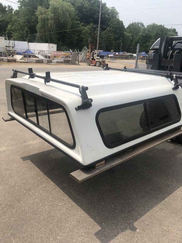 Laser-welded aluminum truck bed cap with roof rack for added cargo space and outdoor sports gear.